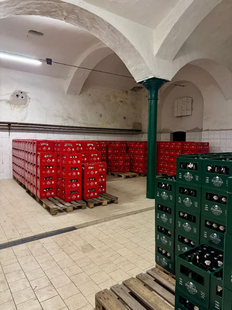Skladový sklep s klenutým stropem a bednami nápojů STADIONER na paletách